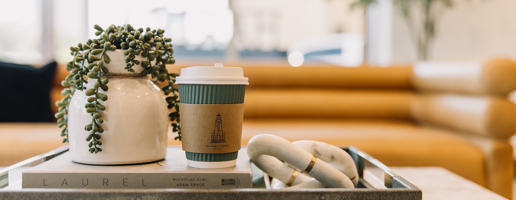 A coffee table with a plant and a cup of coffee in the Harden leasing office in Downtown Fort Worth